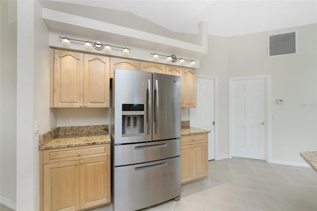 kitchen featuring stainless steel fridge, light stone counters, light brown cabinetry, and vaulted ceiling