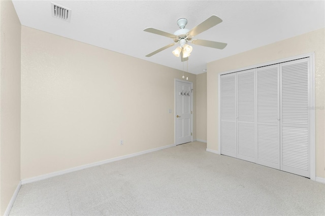 unfurnished bedroom with ceiling fan, light carpet, and a closet