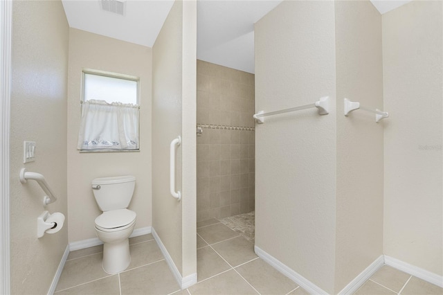 bathroom featuring tile patterned flooring, toilet, and a tile shower