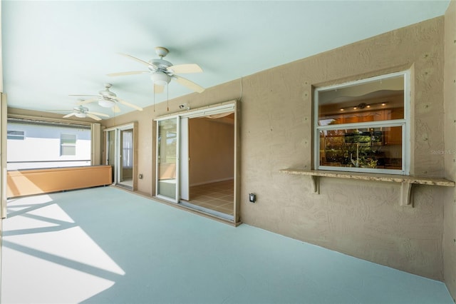 unfurnished sunroom featuring ceiling fan