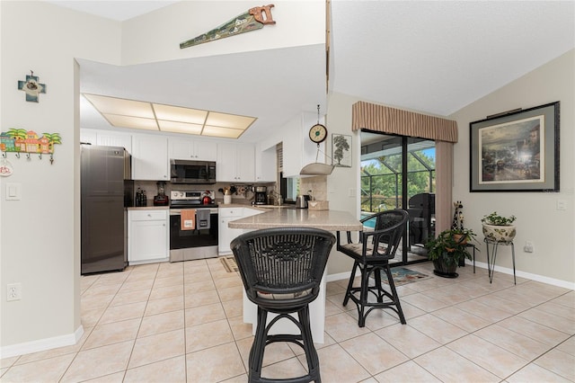 kitchen featuring kitchen peninsula, white cabinetry, stainless steel appliances, and a breakfast bar area