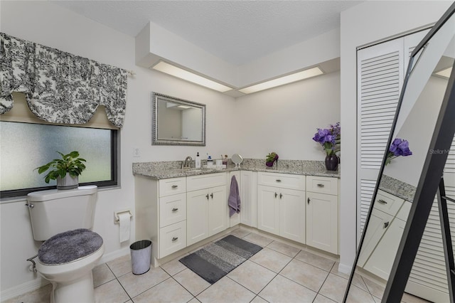 bathroom featuring tile patterned floors, vanity, a textured ceiling, and toilet