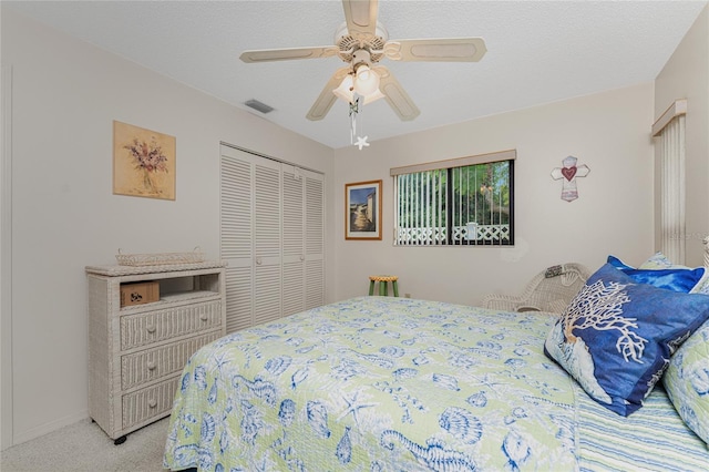 carpeted bedroom with a textured ceiling, a closet, and ceiling fan