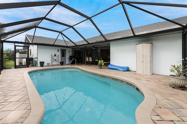 view of pool featuring glass enclosure, ceiling fan, and a patio area