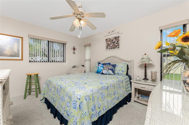 carpeted bedroom featuring ceiling fan and a textured ceiling