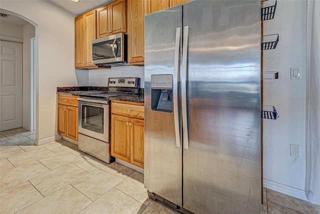 kitchen with appliances with stainless steel finishes, tasteful backsplash, and light tile patterned floors