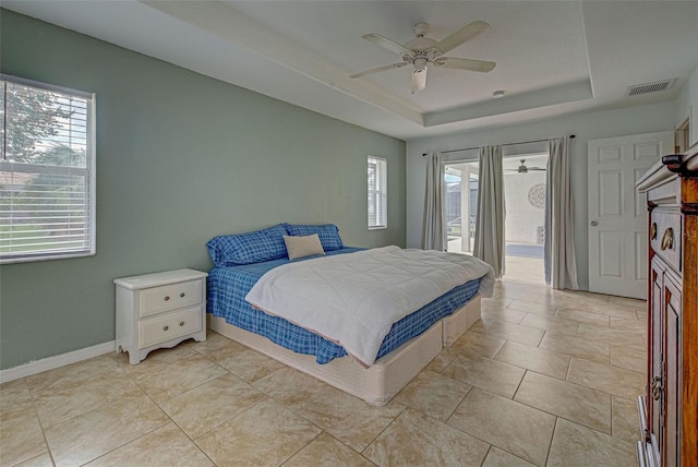 tiled bedroom featuring a raised ceiling, multiple windows, and ceiling fan