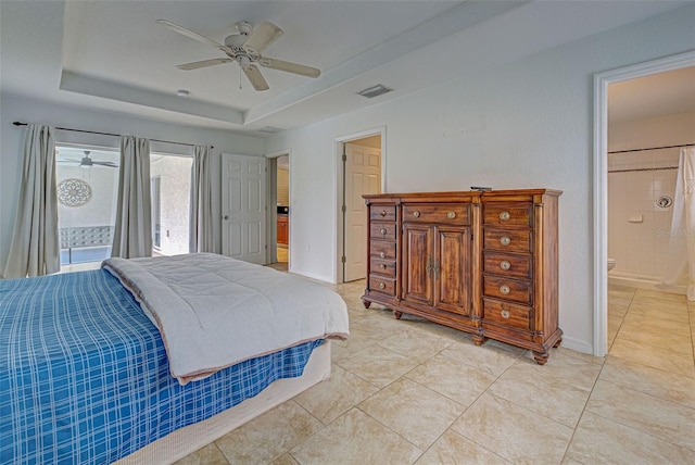 bedroom with ensuite bathroom, ceiling fan, and a raised ceiling