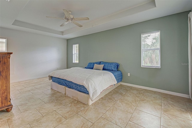 bedroom featuring a raised ceiling, multiple windows, and ceiling fan