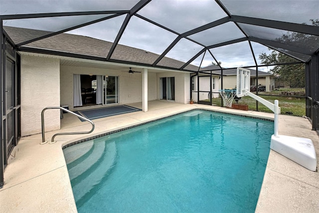 view of swimming pool with ceiling fan, a patio, and glass enclosure