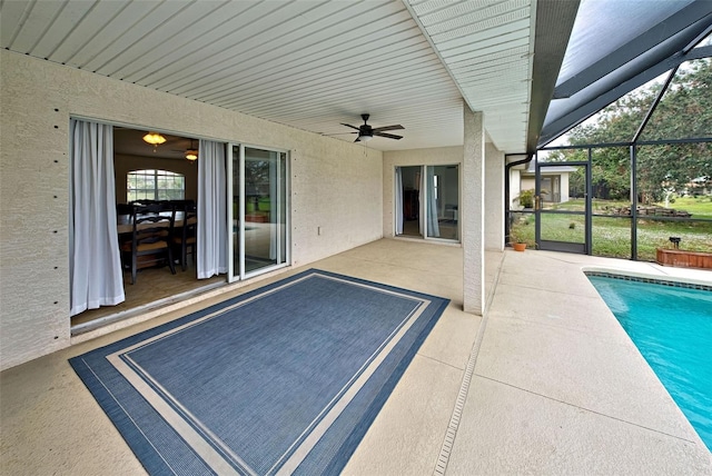 view of swimming pool featuring glass enclosure, ceiling fan, and a patio