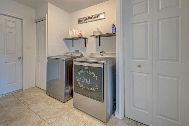 clothes washing area featuring light tile patterned floors and washing machine and clothes dryer