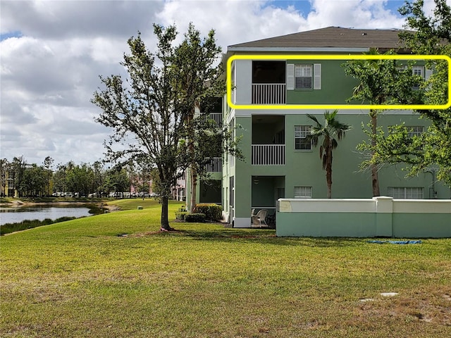 rear view of house featuring a water view and a yard