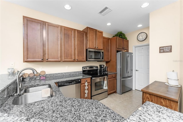 kitchen featuring sink, light tile patterned floors, stainless steel appliances, and stone counters