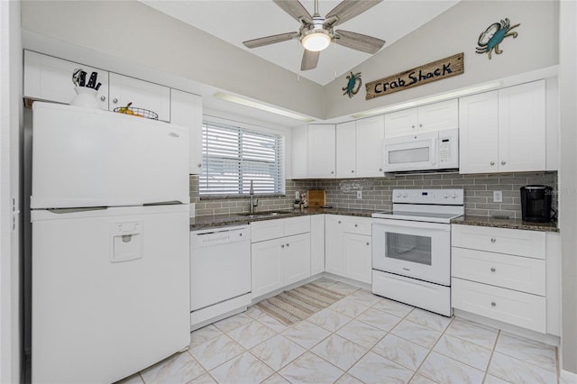 kitchen featuring lofted ceiling, white appliances, dark stone counters, sink, and white cabinetry