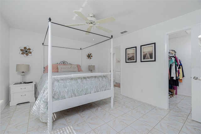 bedroom with ceiling fan, a spacious closet, a textured ceiling, and a closet