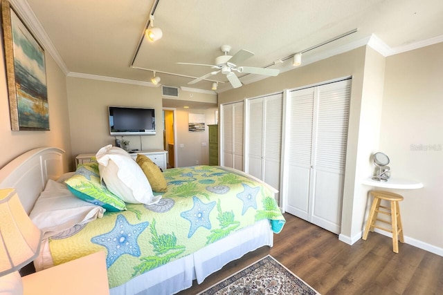 bedroom featuring track lighting, ornamental molding, two closets, ceiling fan, and dark hardwood / wood-style floors