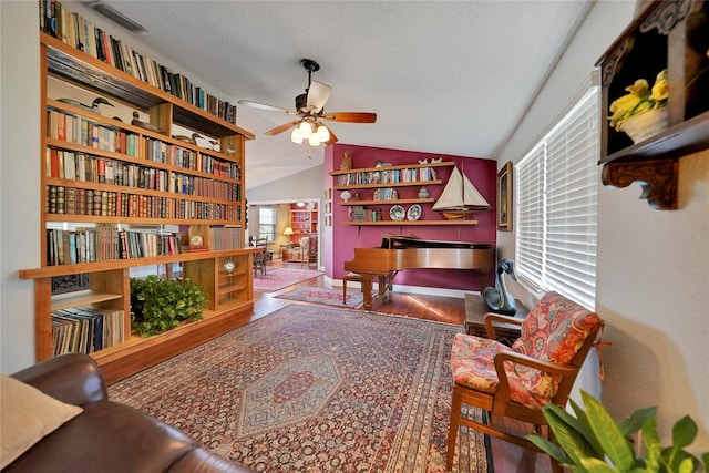 sitting room with ceiling fan, wood-type flooring, lofted ceiling, and plenty of natural light