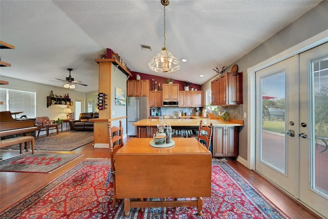 kitchen with lofted ceiling, french doors, decorative light fixtures, a kitchen island, and stainless steel appliances