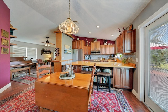 kitchen with pendant lighting, lofted ceiling, dark hardwood / wood-style floors, ceiling fan, and appliances with stainless steel finishes