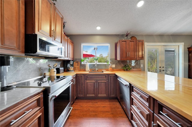 kitchen with french doors, decorative backsplash, a textured ceiling, dark hardwood / wood-style flooring, and stainless steel appliances