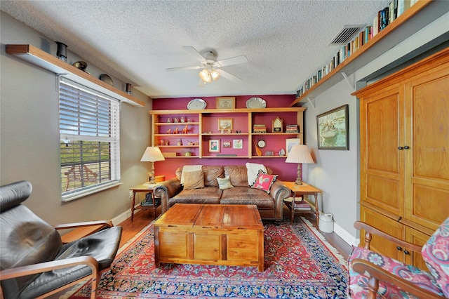 living room with hardwood / wood-style floors, ceiling fan, and a textured ceiling