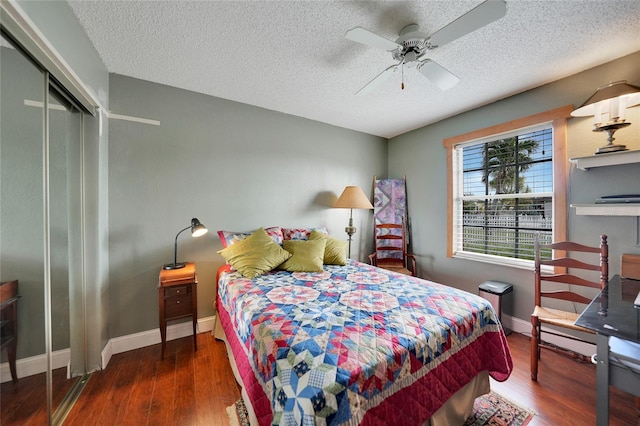 bedroom with a textured ceiling, a closet, ceiling fan, and dark wood-type flooring