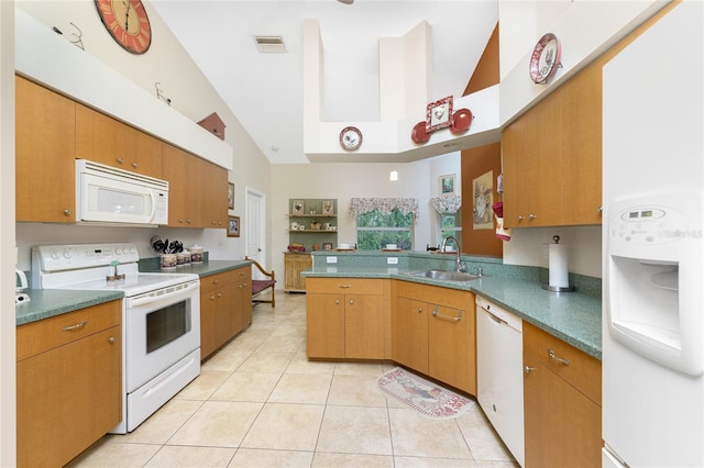 kitchen with visible vents, a sink, white appliances, a peninsula, and light tile patterned floors