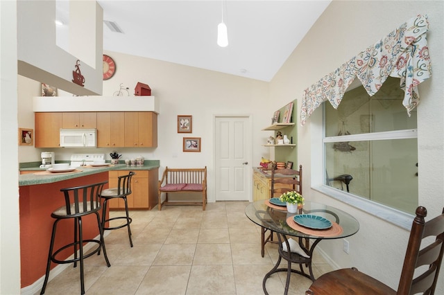 kitchen with light tile patterned floors, white microwave, visible vents, high vaulted ceiling, and a breakfast bar