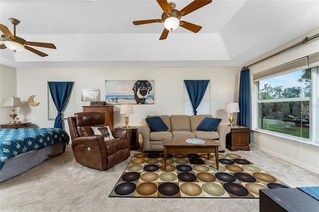 living area with a ceiling fan, carpet, and a tray ceiling