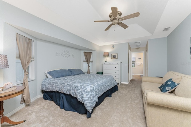 carpeted bedroom with a tray ceiling, visible vents, baseboards, and ceiling fan