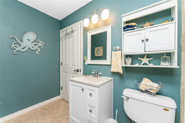 bathroom with toilet, vanity, and baseboards