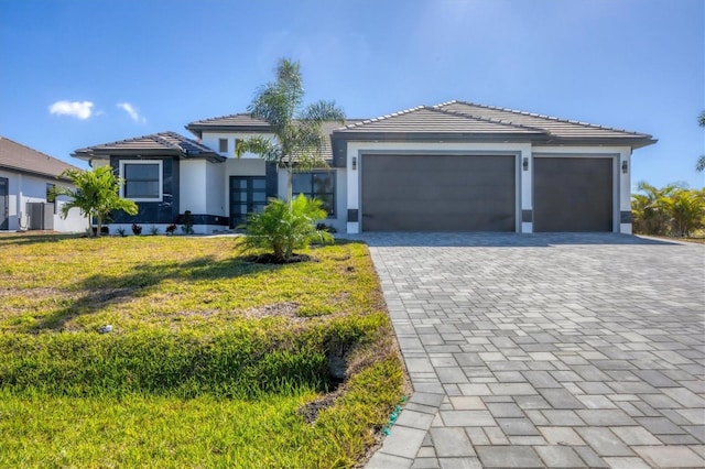 view of front of home with a front yard, a garage, and central air condition unit