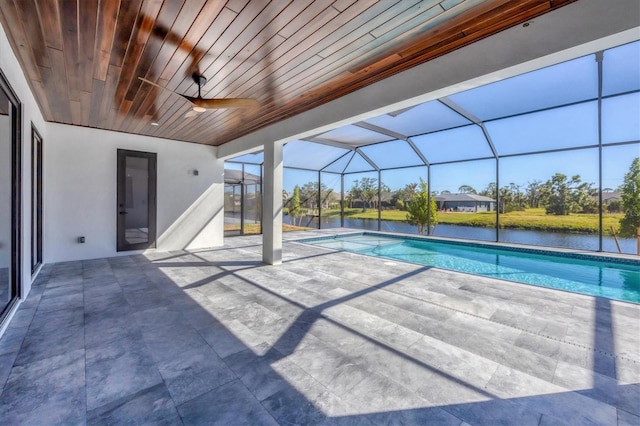 view of swimming pool with glass enclosure, ceiling fan, a water view, and a patio area