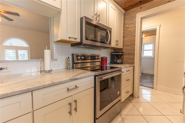 kitchen featuring decorative backsplash, stainless steel appliances, a wealth of natural light, and wooden walls