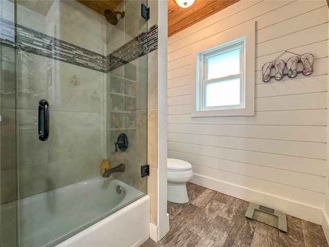 bathroom featuring hardwood / wood-style flooring, toilet, wood walls, and combined bath / shower with glass door