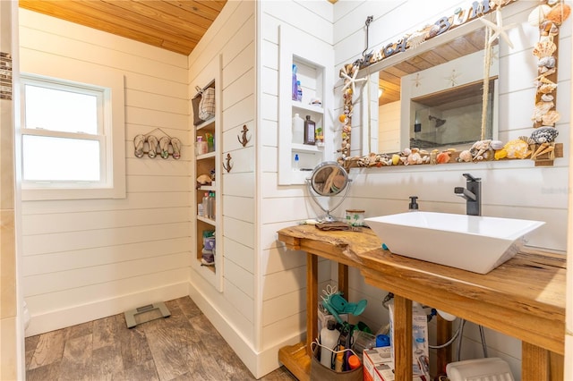 bathroom featuring wood walls, wood-type flooring, wood ceiling, and sink