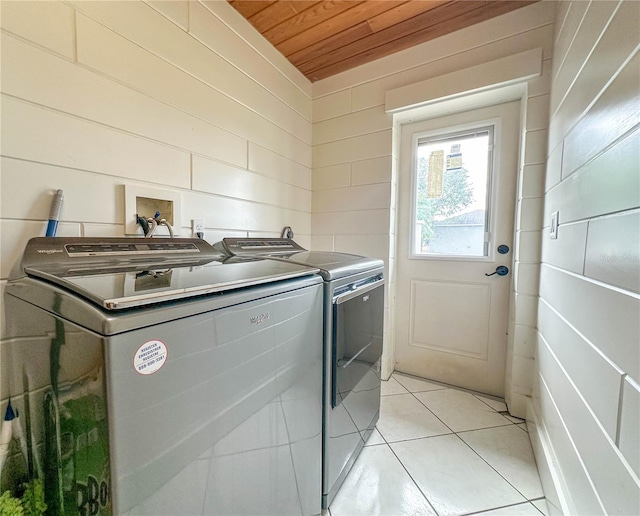 laundry room with wooden walls, light tile patterned flooring, wood ceiling, and independent washer and dryer