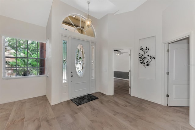 foyer entrance with ceiling fan, light hardwood / wood-style floors, and a high ceiling