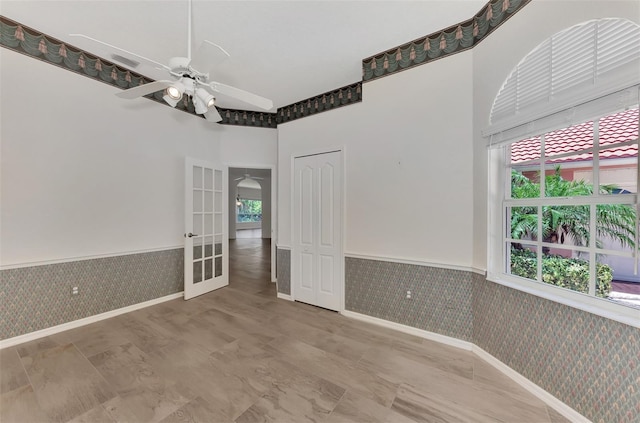 empty room featuring ceiling fan, a towering ceiling, and french doors