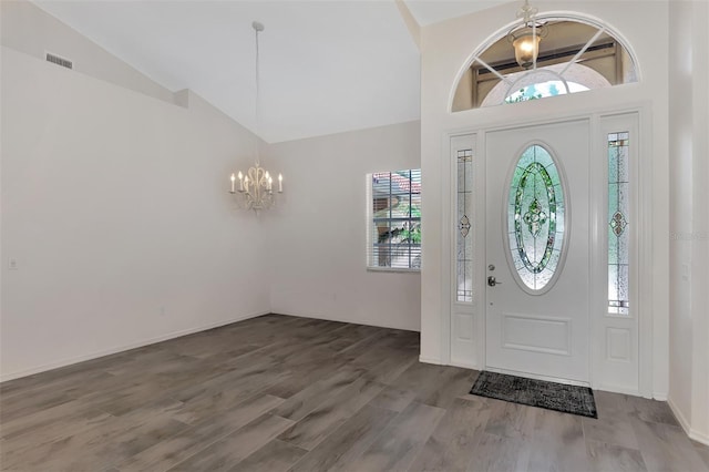 foyer entrance with hardwood / wood-style floors, high vaulted ceiling, and an inviting chandelier