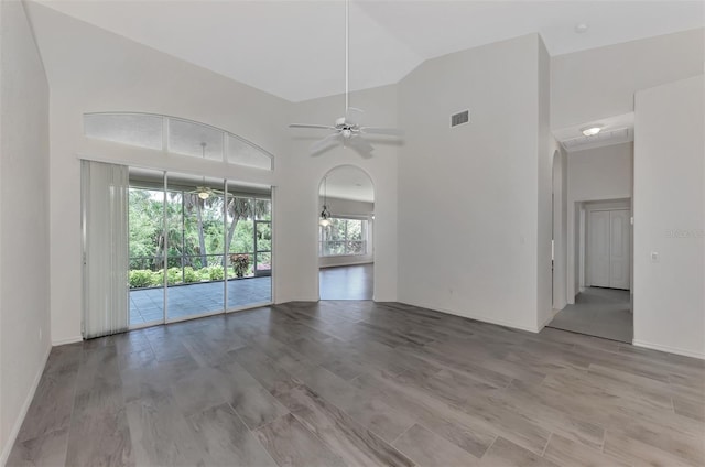 unfurnished living room featuring ceiling fan, high vaulted ceiling, and light wood-type flooring