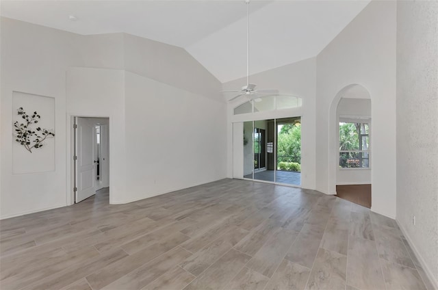 unfurnished living room with light hardwood / wood-style floors, high vaulted ceiling, and ceiling fan