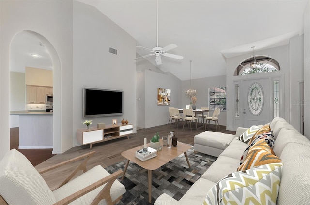 living room with dark hardwood / wood-style flooring, high vaulted ceiling, and ceiling fan with notable chandelier