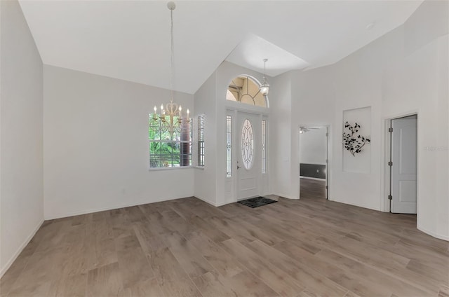 entryway featuring light wood-type flooring, high vaulted ceiling, and a notable chandelier