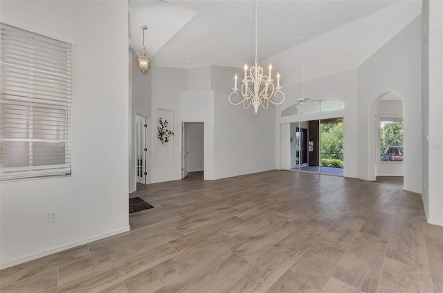 spare room featuring light hardwood / wood-style flooring, high vaulted ceiling, and ceiling fan with notable chandelier