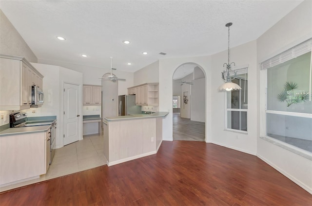 kitchen featuring pendant lighting, light hardwood / wood-style flooring, stainless steel appliances, and a textured ceiling