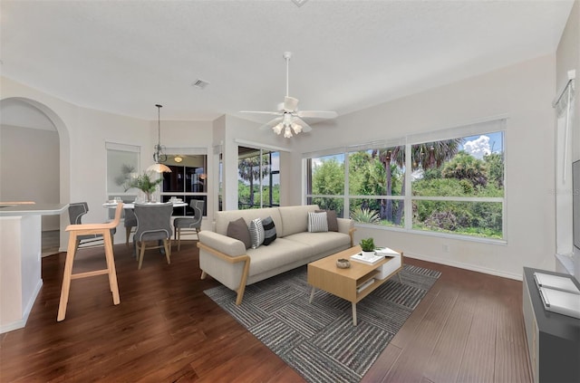 living room with ceiling fan and dark wood-type flooring