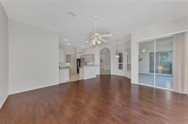 unfurnished living room featuring hardwood / wood-style flooring, ceiling fan, and a textured ceiling