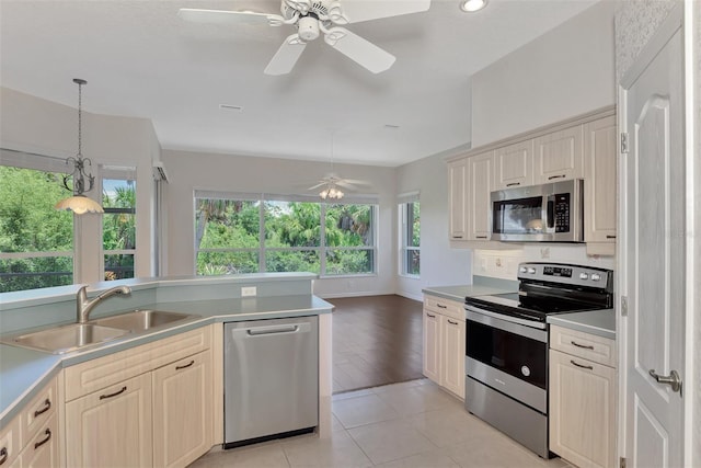 kitchen featuring ceiling fan, sink, hanging light fixtures, appliances with stainless steel finishes, and light wood-type flooring